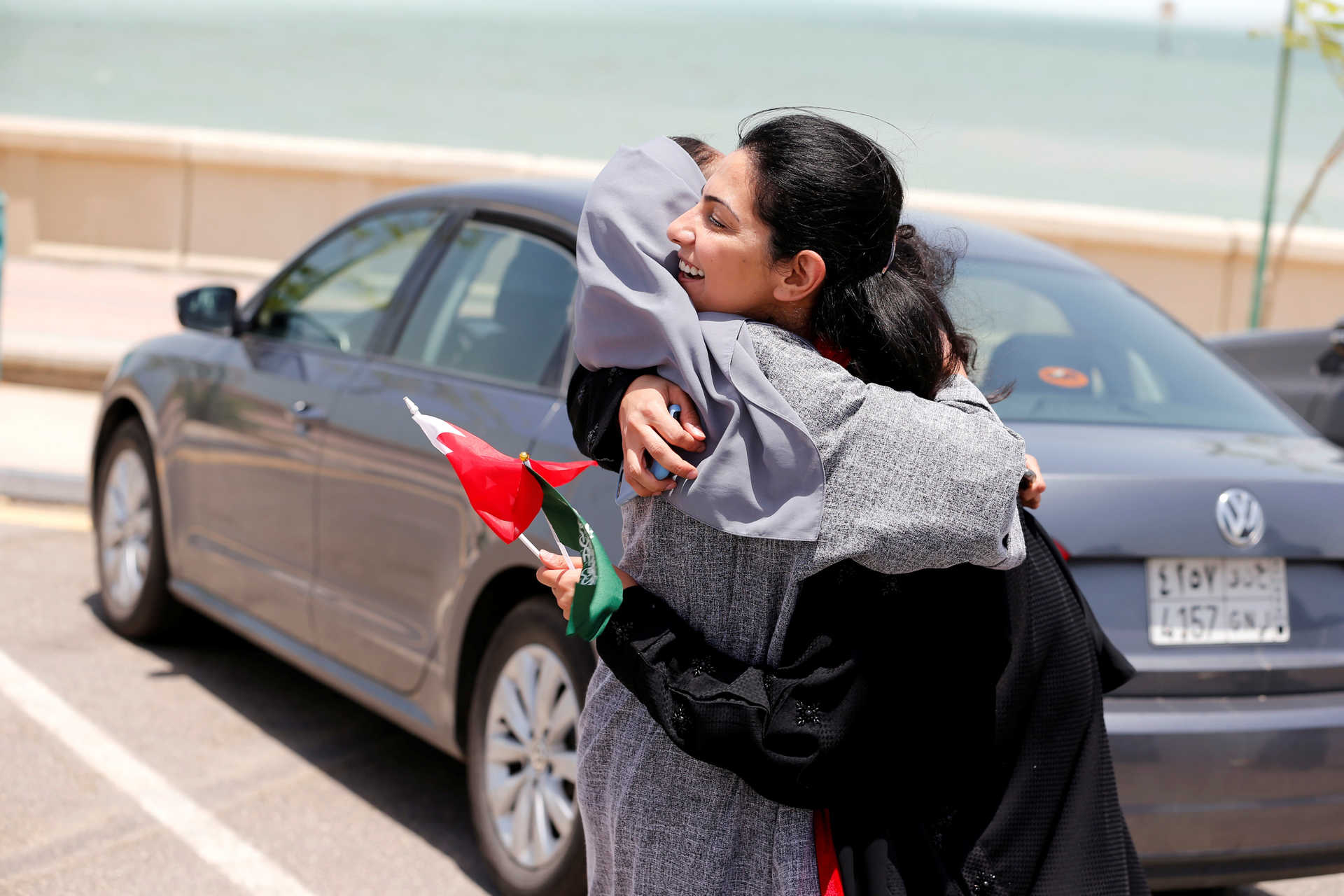 Bahraini Nouf Al Maloud (R) hugs Saudi Zahoor Assiri (L) as they arrive in east Saudi in their cars to promote and congratulate Saudi women on the lifting of the driving ban in Saudi Arabia